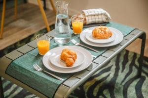 two plates of food on a table with two glasses of orange juice at Studio L'Émeraude - F1 lumineux, hypercentre - CAEN in Caen