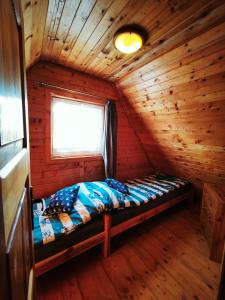 a bed in a log cabin with a window at u HELanki - Domki letniskowe przy samej plaży - Kuźnica in Kuźnica