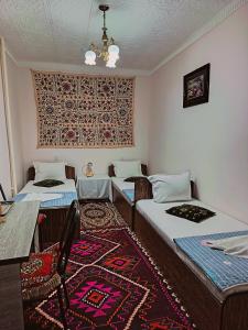 a room with two beds and a table and a rug at Hotel Nazira & Azizbek in Bukhara