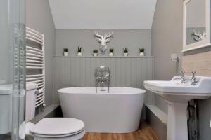 a bathroom with a tub and a toilet and a sink at The Lady Rothschild Stables in Peterborough +30 photos