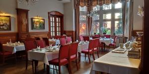 a dining room with white tables and red chairs at Hotel Erbprinzenpalais in Wernigerode