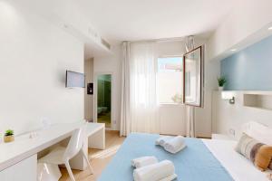 a white room with a desk and a table at Hotel Perla Gaia in San Vito lo Capo