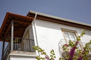 a white house with a balcony and purple flowers at Casa d'Arcã in Alijó