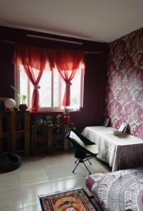 a bedroom with two beds and a window with red curtains at Kiyo's Apartment in Bālāju