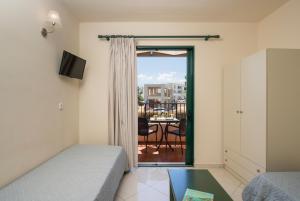 a bedroom with a bed and a balcony with a table at Gianna Apartments in Almyrida