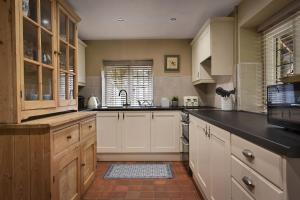 a kitchen with white cabinets and a black counter top at Home Farm Cottage in Peterborough +9 photos