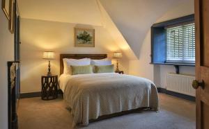 a bedroom with a bed and two lamps and a window at Home Farm Cottage in Peterborough