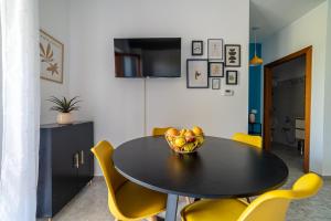 a dining room with a black table and yellow chairs at Fiordaliso in Alba Adriatica