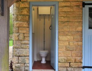 a bathroom with a toilet in a brick wall at Home Farm Cottage in Peterborough