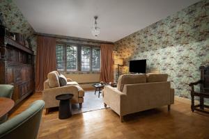 a living room with two chairs and a tv at Rubens Rooms in Peterborough
