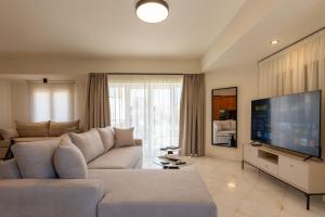 a living room with a couch and a flat screen tv at MAREL Luxury Residence Malia in Malia +13 photos