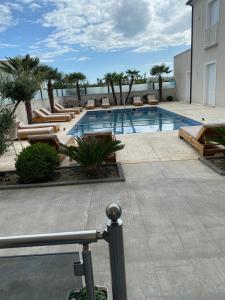 a swimming pool with loungers and chairs next to a building at Hotel del Mar in Shëngjin +22 photos