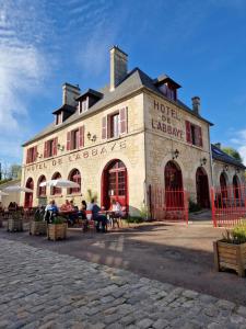 a large building with people sitting outside of it at HOTEL DE L'ABBAYE DE LONGPONT in Longpont