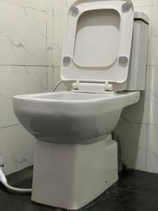 a white toilet with the lid up in a bathroom at Kris Courts in Ibadan