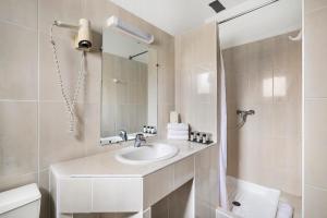 a white bathroom with a sink and a shower at Hotel Le Golfe Bleu in Cavalaire-sur-Mer +39 photos