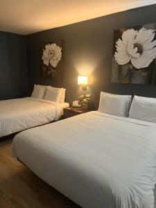 two beds in a hotel room with white sheets at Hôtel Normandie in Rimouski
