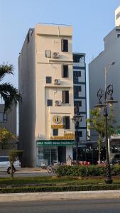 a tall white building with a sign in front of it at Lemon Hotel & Apartment in Danang