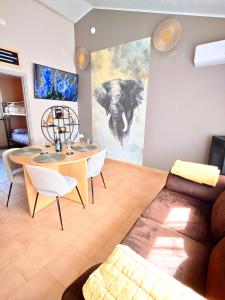 a living room with a table and an elephant painting on the wall at Le Rensy in Ferrières