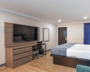 a bedroom with a bed and a desk with a television at Economy Suites Springfield - Extended Stay in Springfield