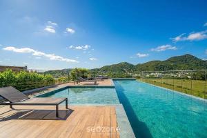 a swimming pool with chairs and a view of mountains at Cozy Studios in Floripa - OKA in Florianópolis