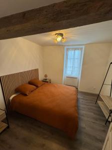 a bedroom with a bed with an orange blanket and a window at L'hotel de ville in Chéroy