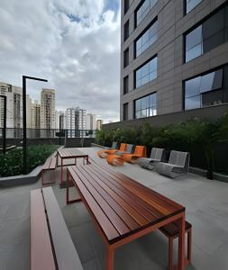 a rooftop patio with a bench and chairs on a building at Studio Tatuapé - SP in São Paulo