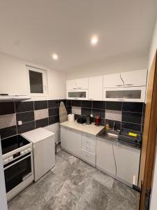 a kitchen with white cabinets and black tiles on the wall at Apartmani Evelin 1 in Veliko Gradište