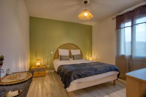 a bedroom with a bed and a green wall at Le Nid du Coderc in Carsac-Aillac