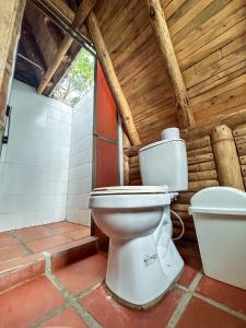 a bathroom with a toilet in a wooden building at Los Pinos EcoHotel in Hobo