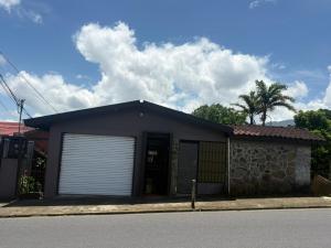 a small house with a garage door on a street at Villa Descanso in Colón