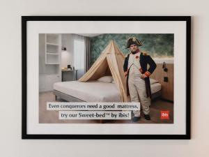 a poster of a man in uniform next to a bed at ibis Brussels Waterloo in Waterloo