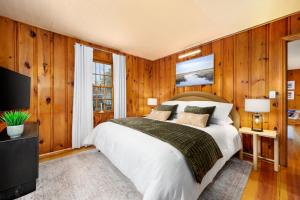 a bedroom with wood paneling and a bed and a television at Charming Cape Cottage in Dennis Port in Dennis Port