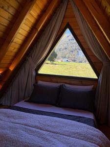 a bed in a tent with a large window at Chalé Recanto da Ema in Urubici