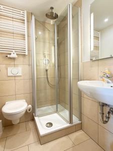 a bathroom with a shower and a toilet and a sink at Hotel St. Ulrich Garni in Ottobeuren +26 photos