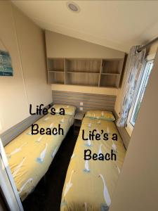 two beds in a room with words life is a beach at Lifes a Beach on Presthaven Sands in Prestatyn