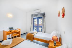a room with two beds and a desk with a computer at HI Beja - Pousada de Juventude in Beja