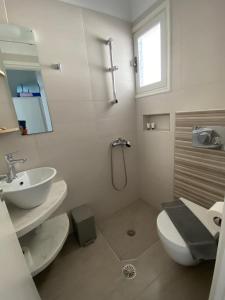 a white bathroom with a sink and a toilet at Pelagos in Aegiali
