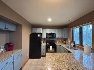a kitchen with a black refrigerator and a sink at Ski-In 5BR Retreat at Boyne Mtn - Walk to Lifts & Fun! in Boyne Falls +29 photos
