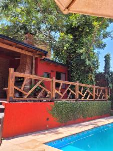 a house with a wooden fence next to a swimming pool at Ombú Guests House in Puerto Iguazú