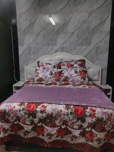 a bed with a purple comforter and red flowers at Camp Inn Lodge in Pietermaritzburg