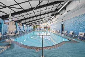 a large indoor swimming pool with chairs and tables at The Barclay Towers Hotel and Resort in Virginia Beach