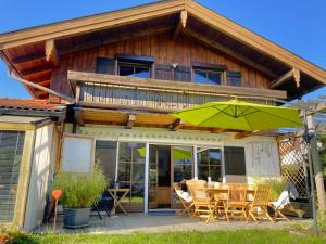 a house with a table and chairs and an umbrella at AlpenLodge Chiemsee in Nußdorf