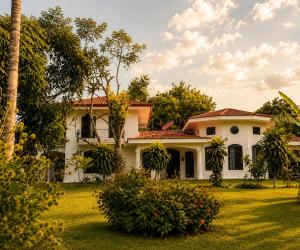 a white house with a palm tree in the yard at Villa Sulterra in Tambor
