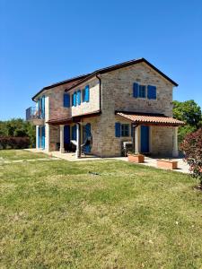 a stone house with blue windows and a yard at Villa Francesca with Private Pool & Designer Interior in Kaštel