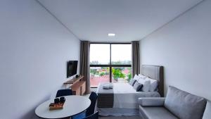 a bedroom with a bed and a couch and a table at Acqua Beach Residence by CTA in Tamandaré
