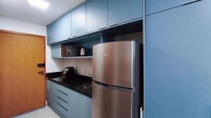 a kitchen with a stainless steel refrigerator and blue cabinets at Acqua Beach Residence by CTA in Tamandaré