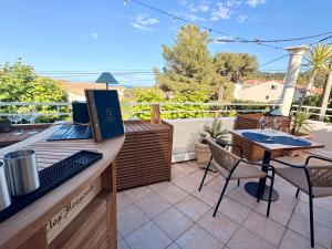 a patio with a table and chairs and a laptop at Hôtel Le Clos du Dramont in Saint-Raphaël
