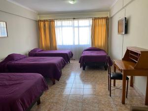 ein Hotelzimmer mit drei Betten und einem Klavier in der Unterkunft HOTEL ASTORE Matta 2537 in Antofagasta