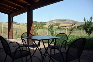 a table and chairs on a porch with a view of a field at Agriturismo Arona in Sperlinga