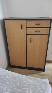 a wooden cabinet with two doors next to a bed at Apartmán Lhota in Náchod
